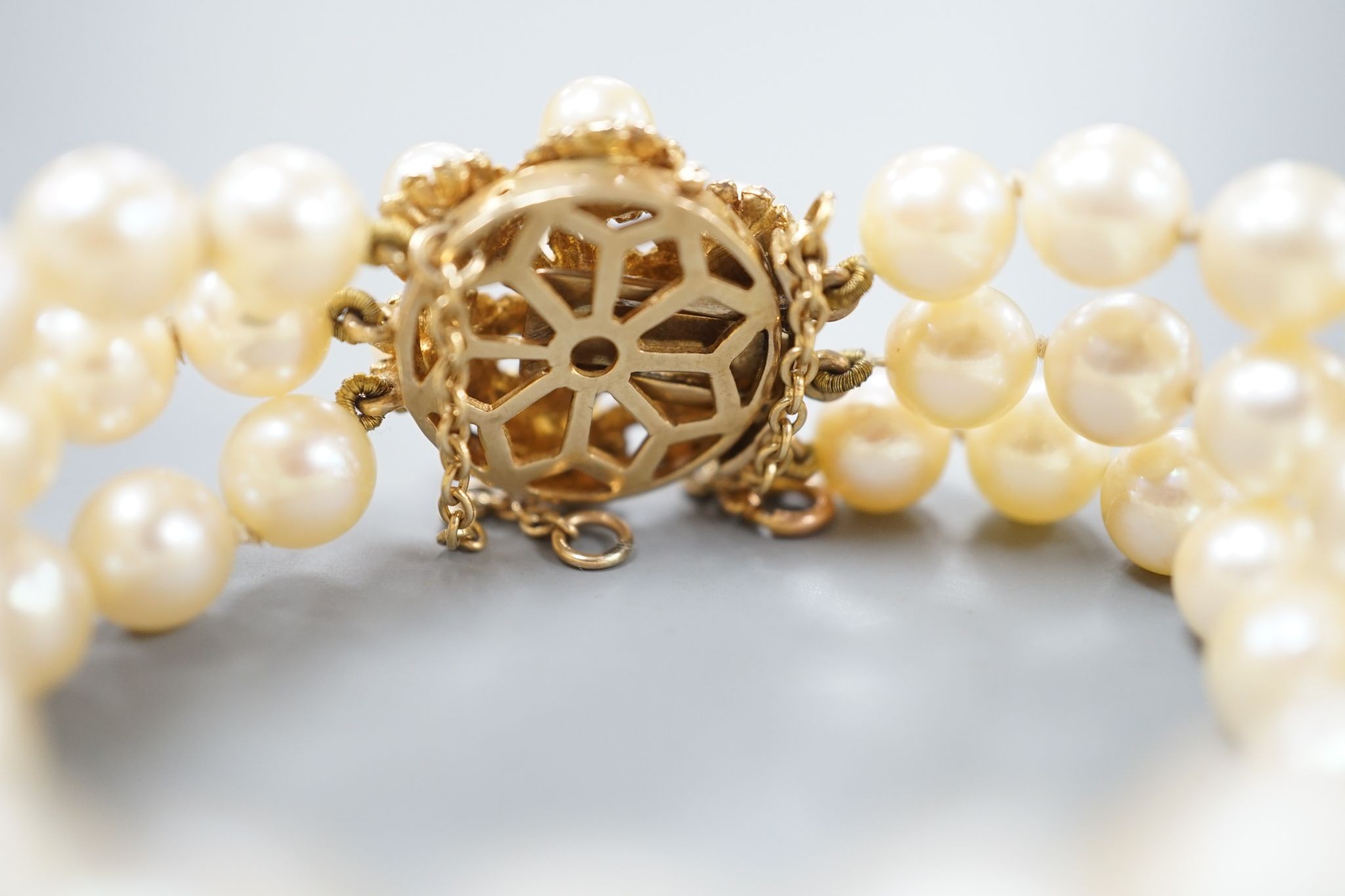 A triple strand cultured pearl bracelet, with yellow metal and cultured pearl cluster set clasp, approx. 16cm.